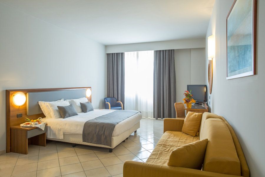 Camera Deluxe del Blu Hotel con letto matrimoniale, divano e finestra